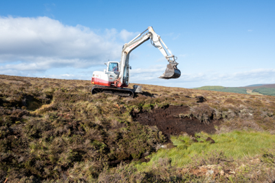 Excavator revegetating bare peat slope